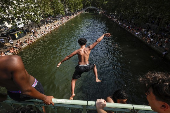 epaselect epa13052276 A young man jumps from a bridge to cool off in the Canal Saint-Martin, in Paris, France, 20 June 2026. An intense heatwave is gripping Western and Central Europe, pushing tempera ...