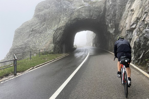 Rennradfahrer auf dem nebligen Sustenpass in den Schweizer Alpen, der die Kantone Uri und Bern verbindet, Schweiz. *** Racing cyclist on the misty Susten Pass in the Swiss Alps, which connects the can ...