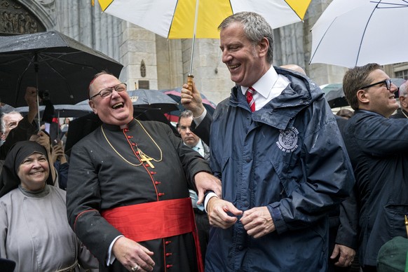 Archbishop of New York Cardinal Timothy Dolan, left, shares a light moment with New York Mayor Bill de Blasio during the annual Columbus Day Parade in New York Monday, Oct 9, 2017. (AP Photo/Craig Rut ...