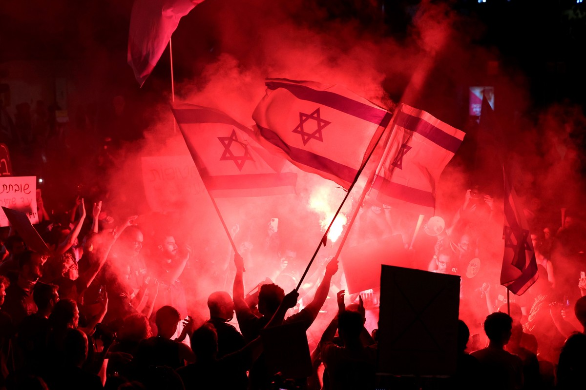 epa11384388 Protesters light flares as they take to the streets to call on the Israeli cabinet to sign a hostage deal and hold early elections during a demonstration outside the Kirya military headqua ...