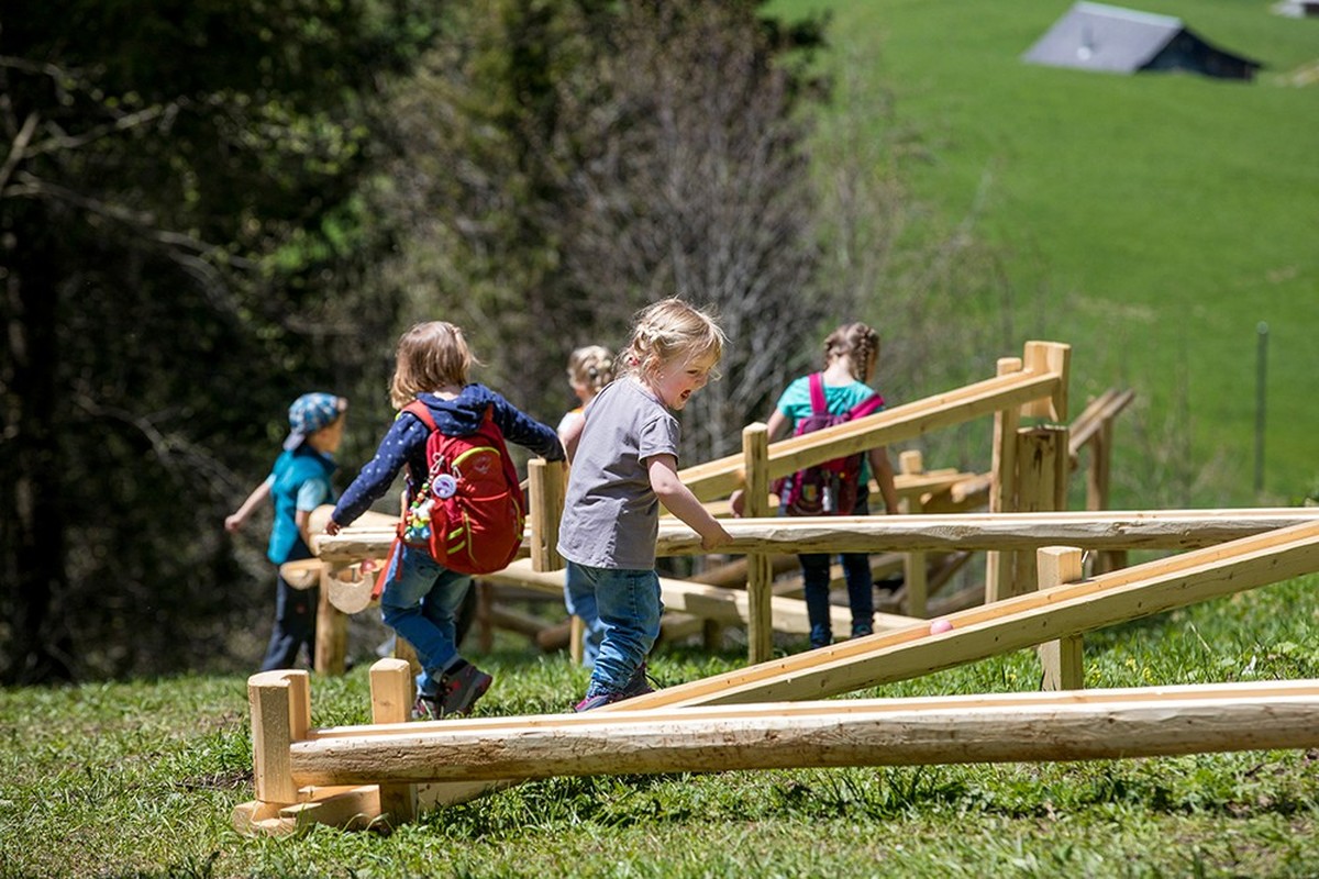 Die Kinder spielen an den fix installierten Holzmurmelbahnen am Kugelweg im Hasliberg. Kugelbahnen Kugelweg Hasliberg Haslital Schweiz Wandern mit Kindern