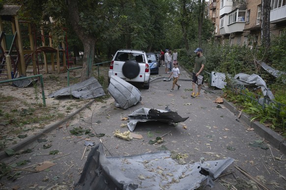 Local residents pass by debris in Kyiv, Ukraine, Wednesday, Aug. 30, 2023, that fell down from their damaged house after a Russian massive rocket attack . Over 20 rockets and drones have been shot dow ...