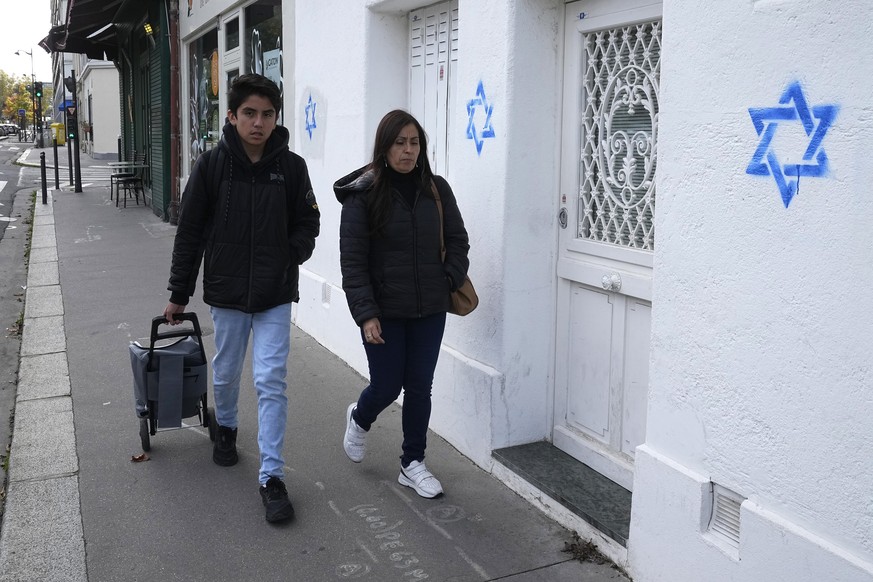 People walk by Stars of David tagged on a wall Tuesday, Oct. 31, 2023 in Paris. Paris police chief Laurent Nunez described the graffiti as anti-Semitic and said police are investigating. (AP Photo/Mic ...