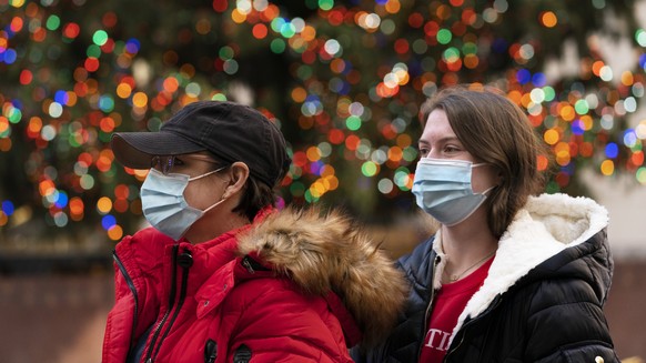 People walk by the Rockefeller Center Christmas Tree, Thursday, Dec. 3, 2020 in New York. What