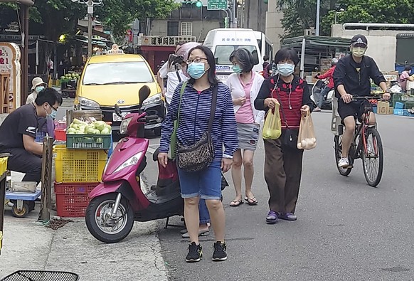 People wear face masks to curb the spread of COVID-19 as they walk in Taipei, Taiwan, Tuesday, Oct. 19, 2021. (AP Photo/Chiang Ying-ying)