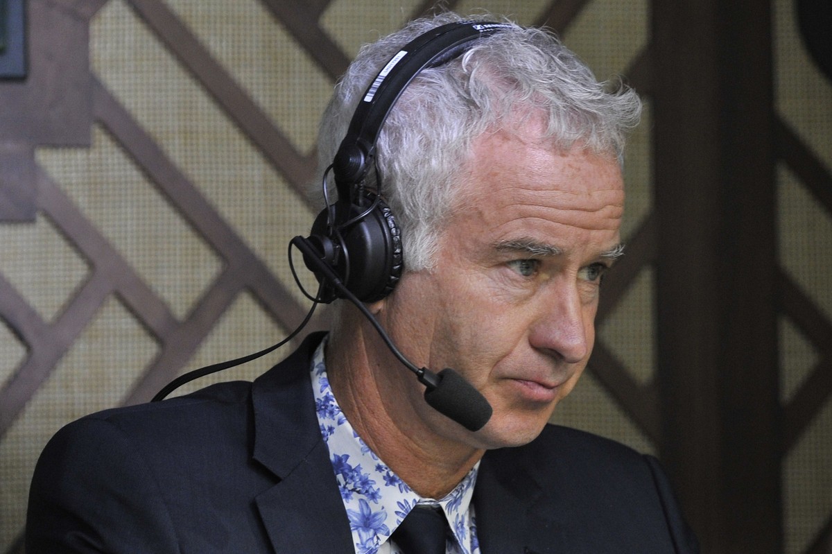 Former champion tennis player John McEnroe sits in the commentary box at centre court as France's Jo-Wilfried Tsonga plays against Serbia's Novak Djokovic during their men's singles fou ...