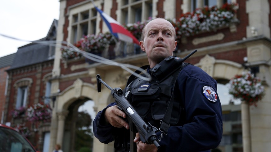 A policeman secures a position in front of the city hall after two assailants had taken five people hostage in the church at Saint-Etienne-du -Rouvray near Rouen in Normandy, France, July 26, 2016. Tw ...