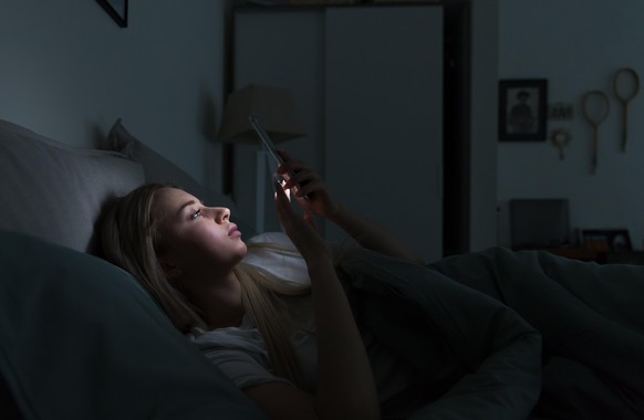 junge Frau im Bett, Smartphone, iphone, erschöpft, müde