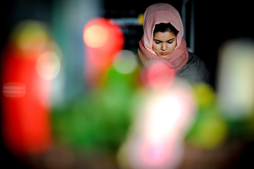 epa08232318 A mourner places flowers and candles at the Brueder Grimm memorial in Hanau, Germany, 20 February 2020. At least nine people were killed in two shootings at shisha bars in Hanau, police sa ...