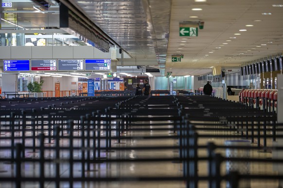 Security officers walk through the check-in hall of the terminal 1 of the Geneve Aeroport, in Geneva, Switzerland, Tuesday, March 24, 2020. Due to the COVID-19 Coronavirus pandemic a large number of f ...