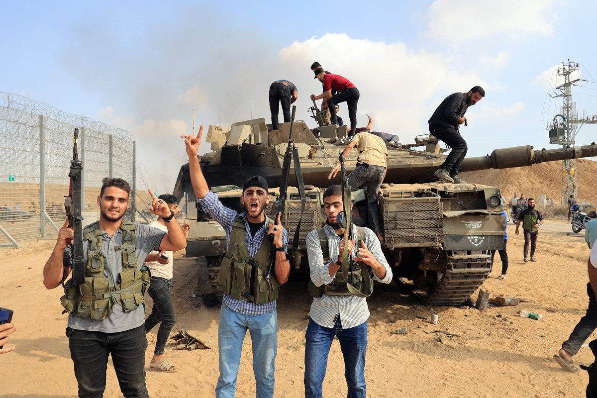 Palestinians take control of an Israeli tank after crossing the border fence with Israel from Khan Yunis in the southern Gaza Strip on Saturday October 7, 2023. Barrages of rockets were fired at Israe ...