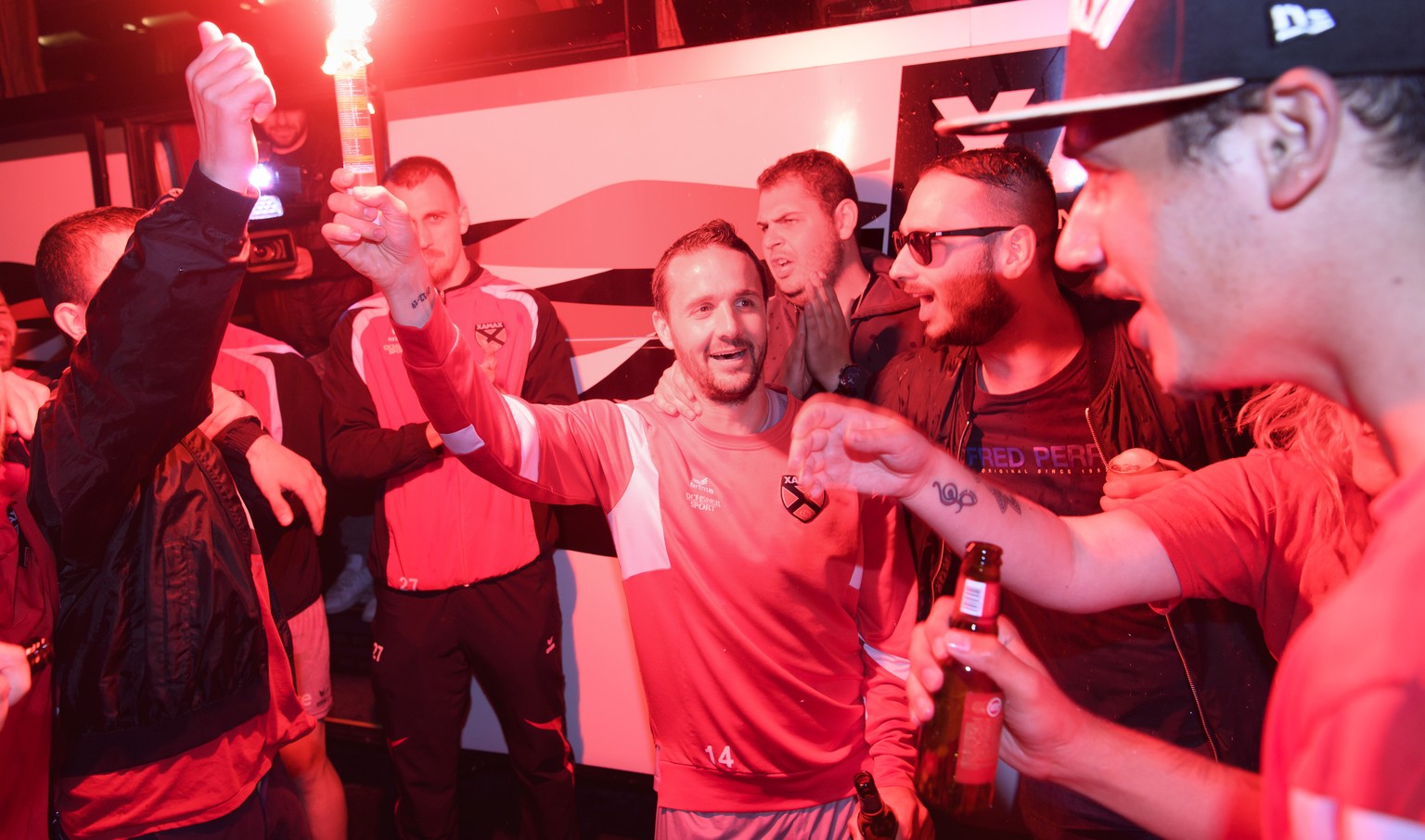 Le joueur de l’equipe de football de Challenge League Neuchatel Xamax FCS Raphael Nuzzolo, centre, fete avec une torche l&#039;ascension en Super League avec leurs fans ce mardi 24 avril 2018 au stade ...