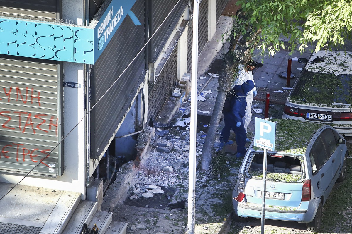 Greek police forensic experts search the area where a 38-year-old woman was killed early Saturday when a bomb she was carrying exploded in her hands outside a bank branch, local police said, in Thessa ...