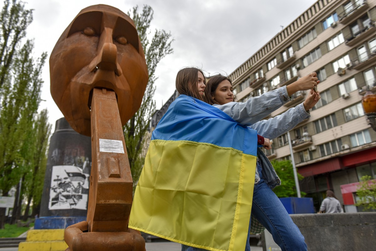 epa09931677 Girls take a selfie in front of the scuplture "Shot yourself" in Kyiv (Kiev), Ukraine, 07 May 2022. The installation shows a man who supposed to resemble Russian president Putin  ...