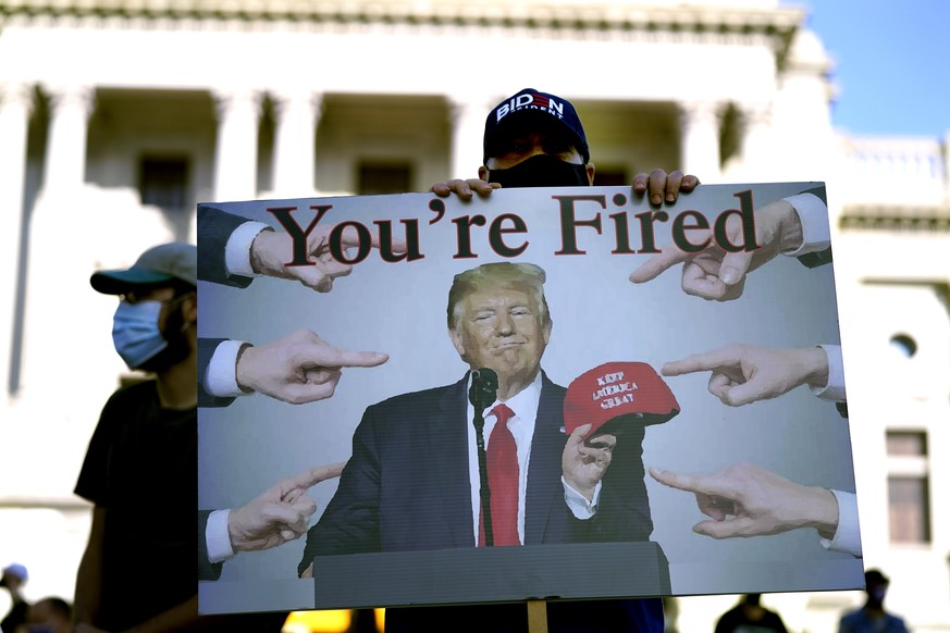 A supporter of President-elect Joe Biden holds a sign referring to President Donald Trump outside the Pennsylvania State Capitol, Saturday, Nov. 7, 2020, in Harrisburg, Pa., after Biden defeated Trump ...