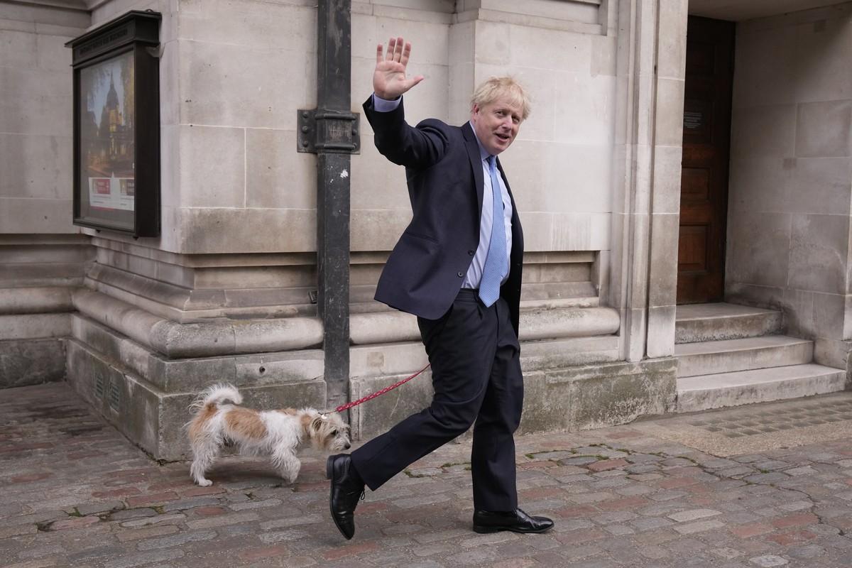 FILE - Britain's Prime Minister Boris Johnson waves at the media as he leaves with his dog Dilyn after voting at a polling station in London, for local council elections, Thursday, May 5, 2022. T ...