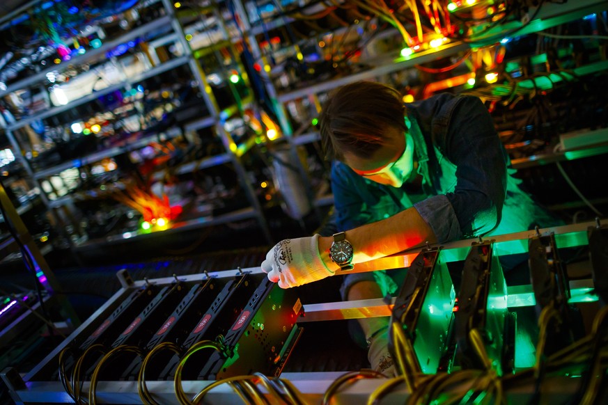 Alpine Mining employee Bertrand Deldon is lit by the LED status lights of electronic boards during a long exposure photograph at a cryptocurrency mine in the small alpine village of Gondo, Switzerland ...