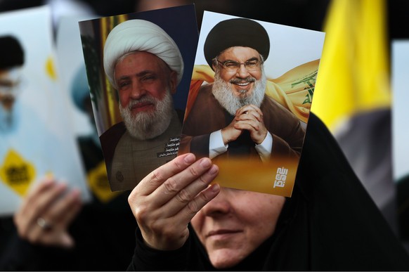 epa12993291 A supporter of Hezbollah carries pictures of Hezbollah leader Sheikh Naim Qassem (L) and late Hezbollah leader Hassan Nasrallah (R) during a gathering to mark 'Resistance and Liberati ...