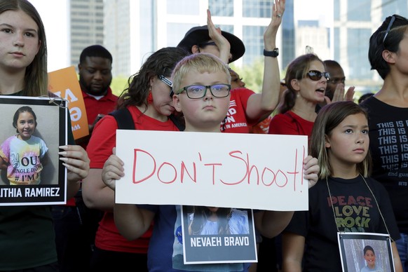 Children hold signs and photos of the Uvalde, Texas school shooting victims during a rally at Discovery Green Park, across the street from the National Rifle Association Annual Meeting held at the Geo ...