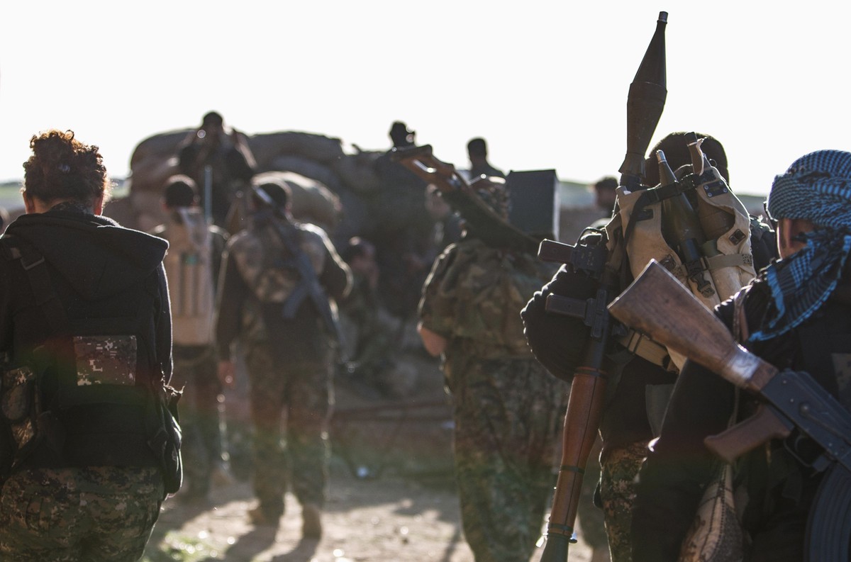 Kurdish People's Protection Units (YPG) fighters carry their weapons as they head towards their positions during what the YPG said was an offensive against them by Islamic State fighters, in the  ...
