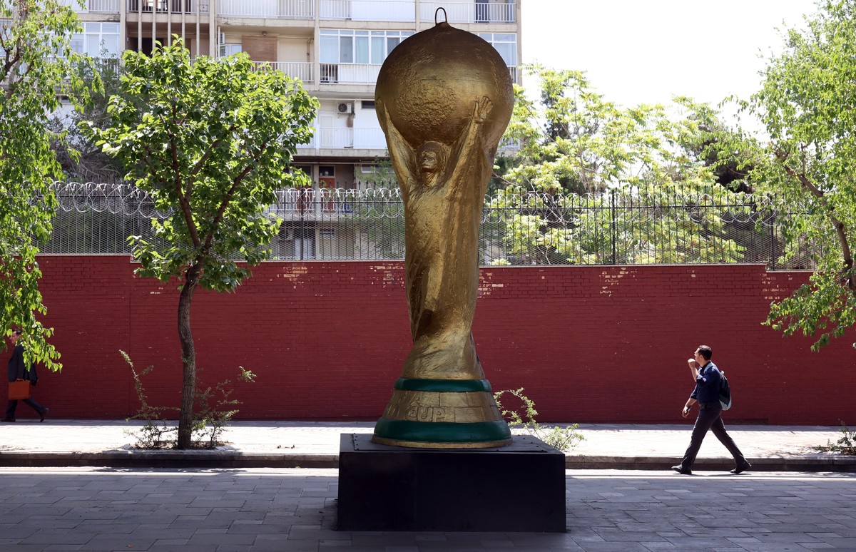 epa13027811 An Iranian man walks next to a replica of the World Cup trophy in a street in Tehran, Iran, 10 June 2026. Iran's football federation says its FIFA World Cup group-stage ticket allocat ...