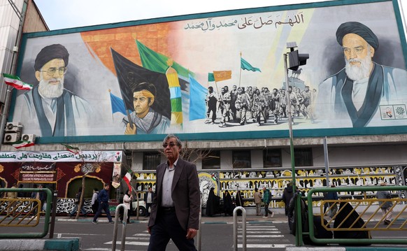 epa12648500 A man walks past a mural depicting Iranian Supreme Leader Ayatollah Ali Khamenei (L, top) and late Supreme Leader Ayatollah Ruhollah Khomeini (R, top) during a funeral ceremony for securit ...