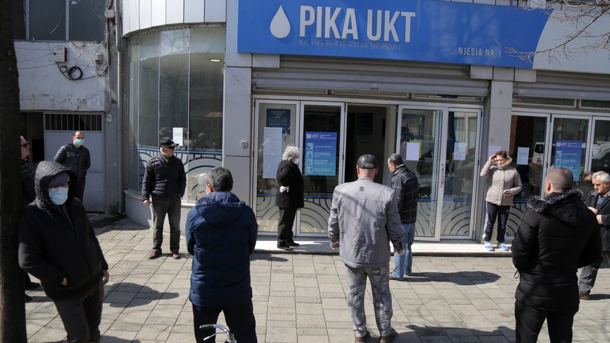 epa08319596 People keep the distance from each other while waiting to pay local taxes in Tirana, Albania, 24 March 2020. The goverment has delivered extra funds to the local goverment to find a place ...