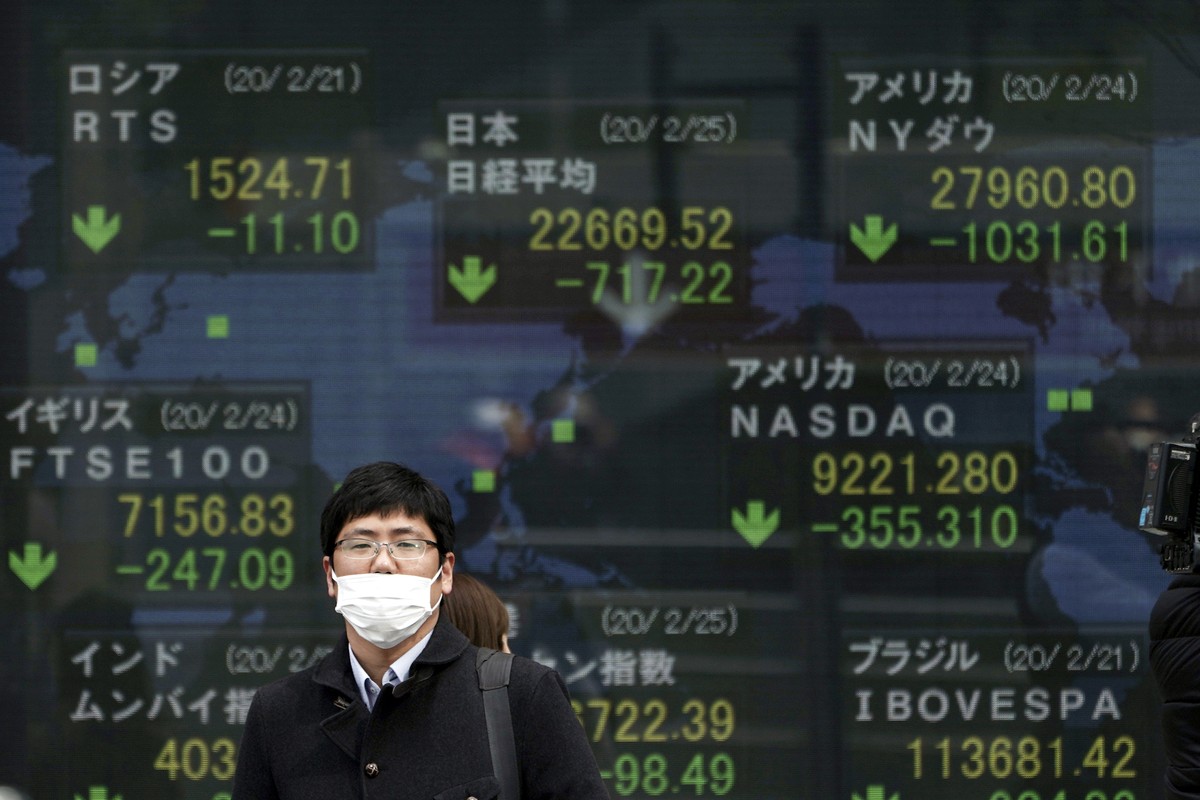 A man stands in front of an electronic stock board showing Japan's Nikkei 225 index and other city's index at a securities firm in Tokyo Tuesday, Feb. 25, 2020. Shares are mostly lower in As ...