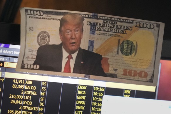 A picture of President Donald Trump on a hundred dollar bill is displayed at a post on the floor of the New York Stock Exchange in New York, Tuesday, Jan. 21, 2025. (AP Photo/Seth Wenig)