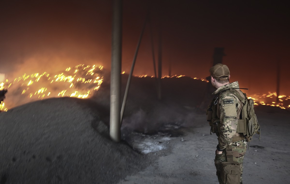 epa09988724 An Ukrainian serviceman looks at a sunflower seeds storage on fire after shelling on a farm close to the front line near the city of Bakhmut, Donetsk region, Ukraine, 31 May 2022. Russian  ...