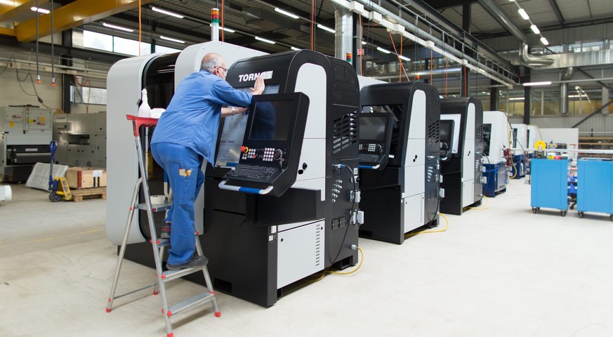 THEMENBILD ZU SWISSMEM STUDIE NUTZEN DER BILATERALEN VERTRAEGE FUER MASCHINENINDUSTRIE --- An employee of Swiss machine tool producer Tornos fixes the company logo onto a machine, captured in Tornos&# ...