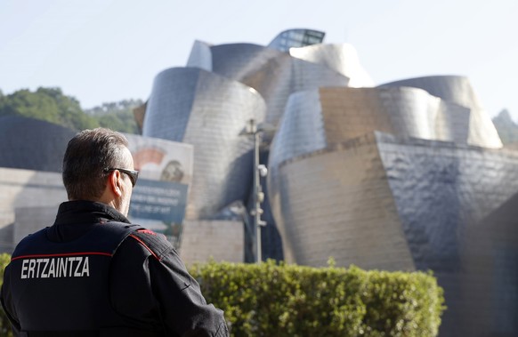 epa09302257 A Basque regional police agent is seen without a facial mask in front of the Guggenheim Museum in Bilbao, Spain, 26 June 2021. The Government passed a new law that allows people to go with ...