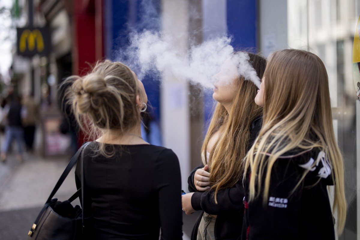 epa10663276 Young people use single-use vaping products in London, Britain, 30 May 2023. The UK government has announced it is cracking down on retailers providing free vape samples to children. The g ...