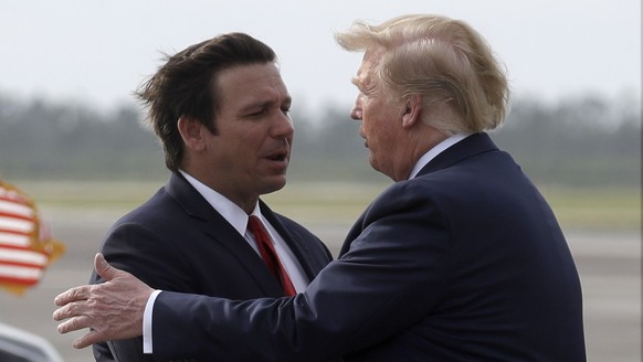 FILE - President Donald Trump shakes hands with Florida Gov. Ron DeSantis as he arrives at Tyndall Air Force Base to view damage from Hurricane Michael, and attend a political rally, May 8, 2019, at T ...