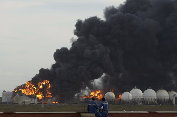 FILE - In this Aug. 27, 2012 file photo, workers of the state oil company, PDVSA, watch a fire that rises over the Amuay refinery near Punto Fijo, Venezuela. Now in Feb. 2019, conditions are so danger ...