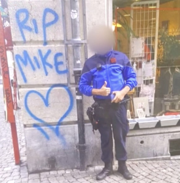 Polizist posiert vor dem Graffiti für Mike Ben Peter in Lausanne