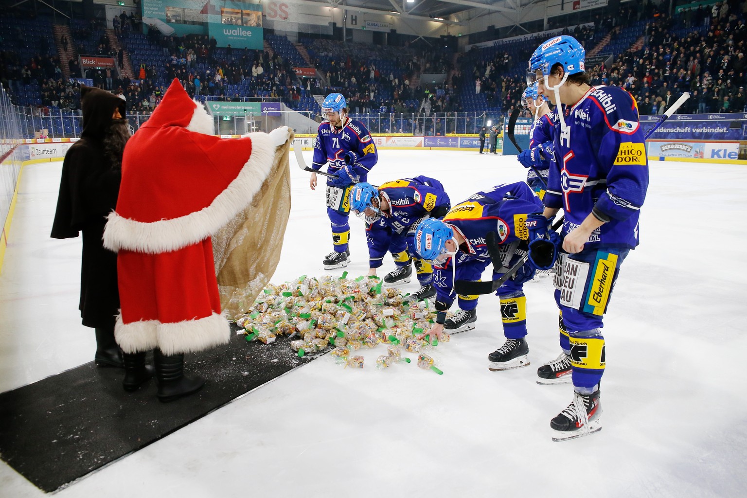 Schmutzli und Samichlaus mit Chlaussaecken fuer die EHC Kloten Stuermer Michael Loosli , Steve Kellenberger , Miro Aaltonen und David Reinbacher , von links , nach dem Eishockey-Meisterschaftsspiel de ...