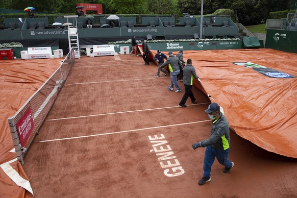 epa09207134 Staff remove the rain cover from the court during the first round match between Benoit Paire of France and Dominik Keeper of Germany at the ATP 250 Geneva Open tennis tournament in Geneva, ...