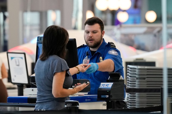 A Transportation Security Administration worker, right, checks boarding documents of a traveler at a security checkpoint in the Nashville International Airport, Thursday, Oct. 2, 2025, in Nashville, T ...