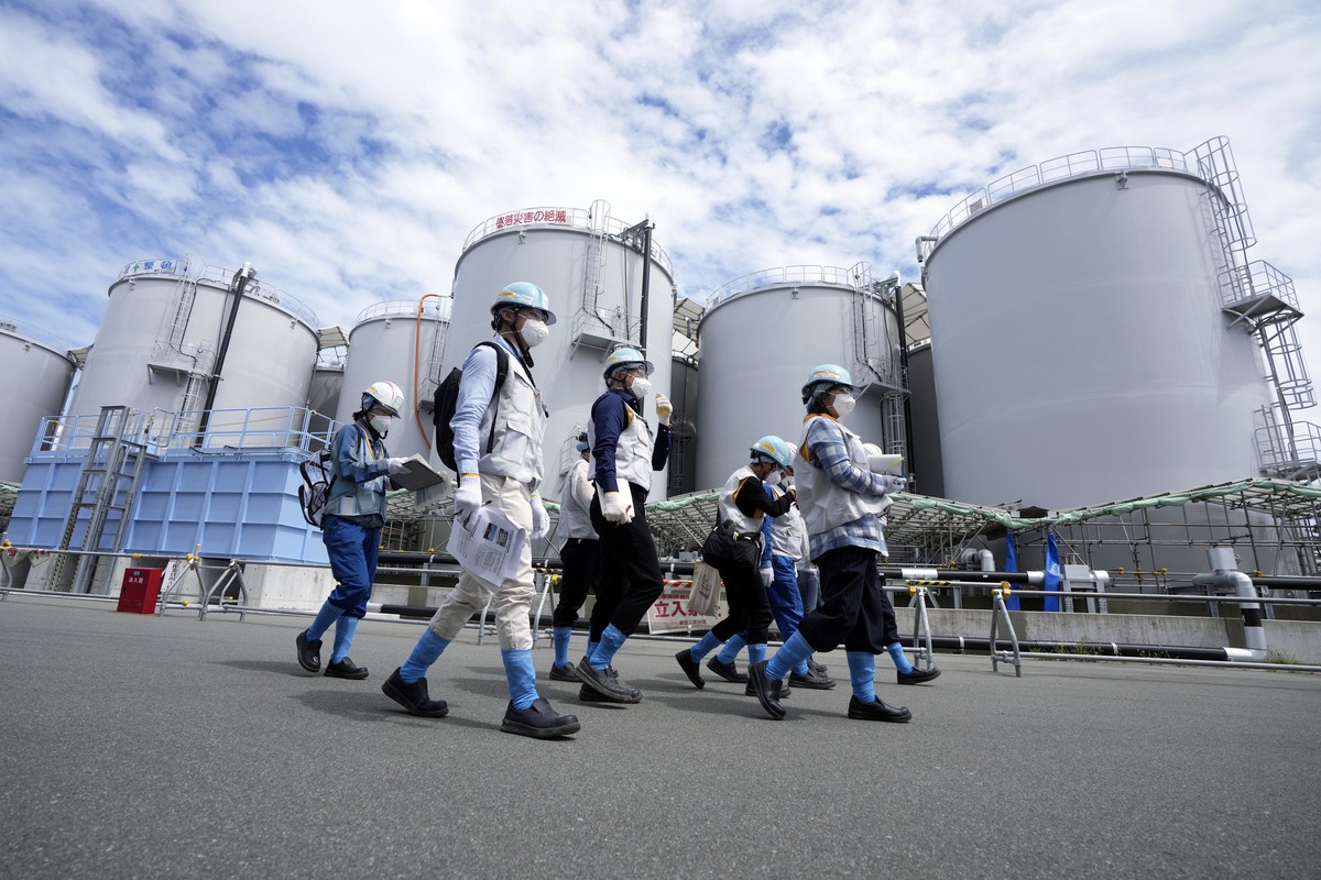 epa10823029 Foreign journalists are guided along with tanks containing treated radioactive wastewater, part of the facility for the releasing treated radioactive water to sea from the Fukushima Daiich ...
