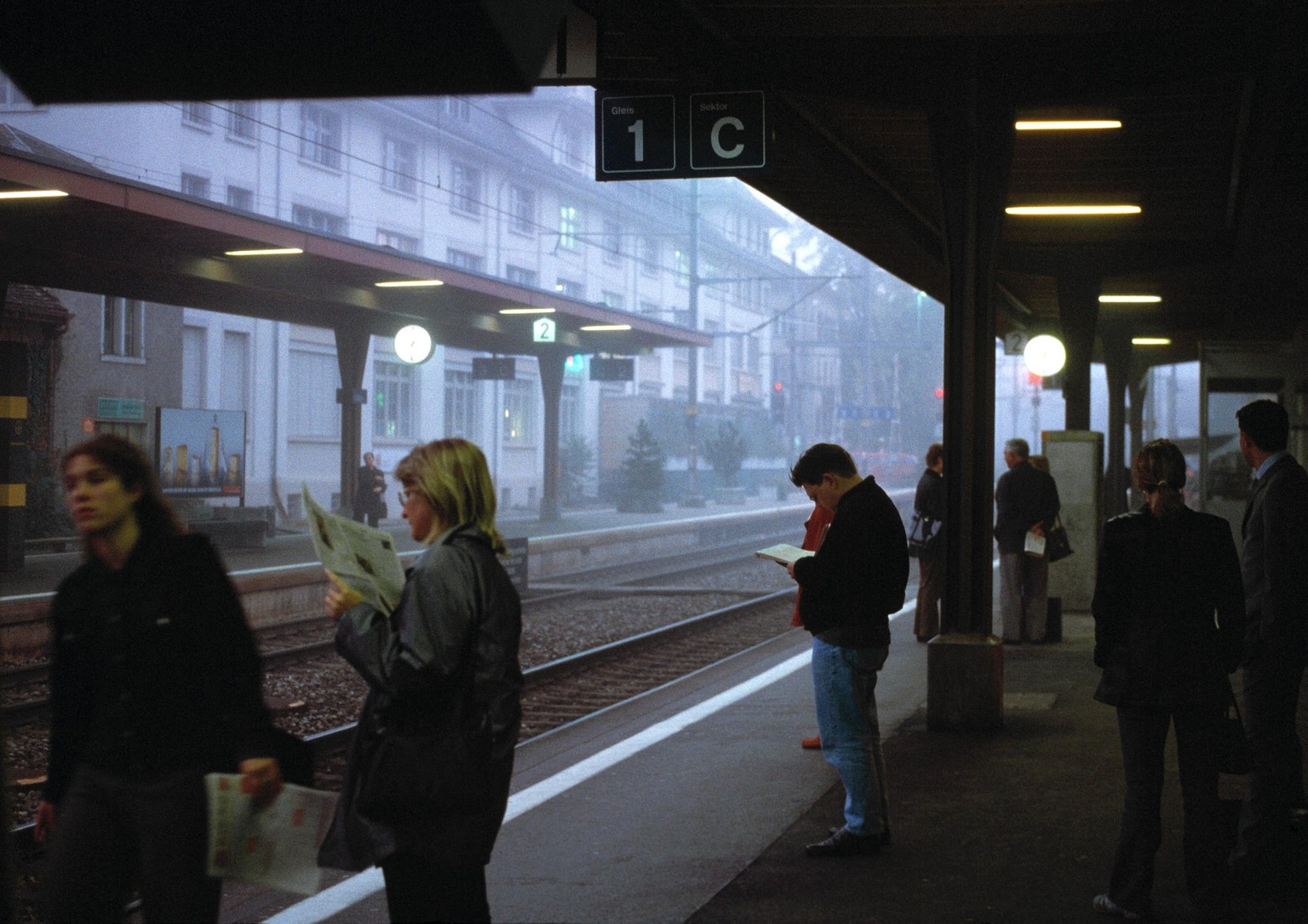 Pendler-Alltag: Wartende Fahrgaeste lesen Gratiszeitungen auf einem Perron im Bahnhof Uster ZH, am 4. Oktober 2001. (KEYSTONE/Mirjam Wanner) : DIA, Nr. 254828]