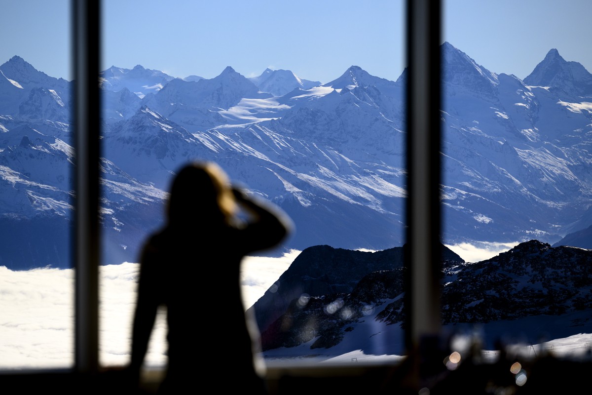 epa11720408 A woman observes the view of the Alps mountains from the newly inaugurated restaurant 'Botta' featuring a solar panel facade at the Glacier 3000 resort in Les Diablerets, Ormont- ...