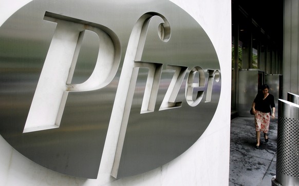 epa08172742 (FILE) - A file image dated 26 June 2006 showing a woman walking past a sign in front of the world headquarters building of Pfizer Inc. in New York, USA (reissued 28 January 2020). New Yor ...