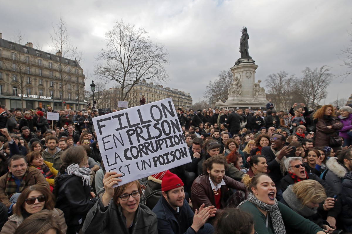 A man holds a placard reading "Fillon Go To Jail, Corruption is a Poison" as activists from left-wing parties and other groups attend a demonstration at the Place de la Republique against co ...