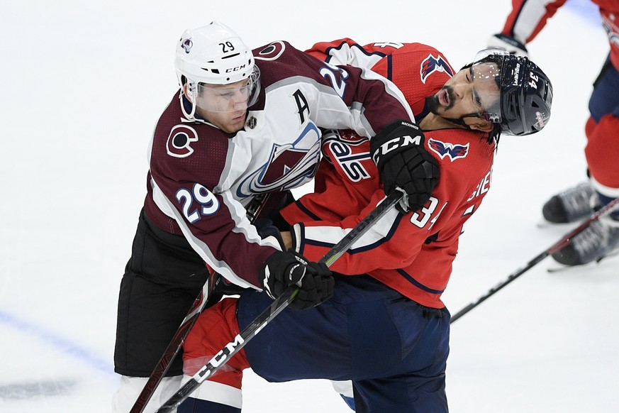 Colorado Avalanche center Nathan MacKinnon (29) hits Washington Capitals defenseman Jonas Siegenthaler (34), of Switzerland, during the third period of an NHL hockey game, Monday, Oct. 14, 2019, in Wa ...