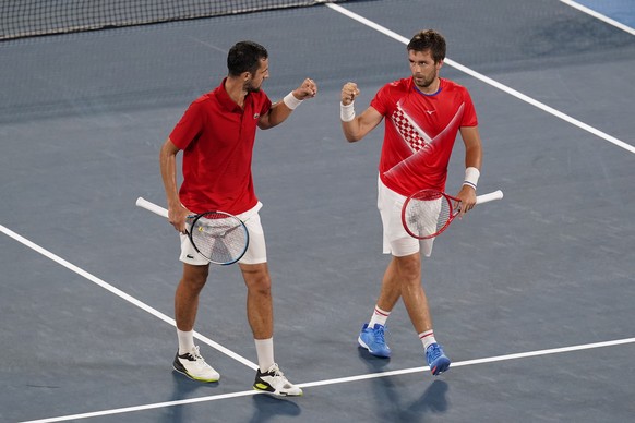 Nikola Mektic, right, and Mate Pavic, of Croatia, bump fists during the quarterfinal round of men&#039;s doubles tennis competition against Kei Nishikori, and Ben McLachlan, of Japan, at the 2020 Summ ...