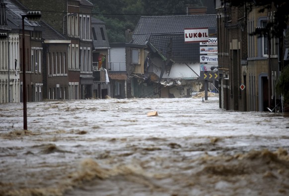 Houses are damaged as floodwaters run down a main street in Pepinster, Belgium, Thursday, July 15, 2021. Heavy rainfall is causing flooding in several provinces in Belgium with rain expected to last u ...