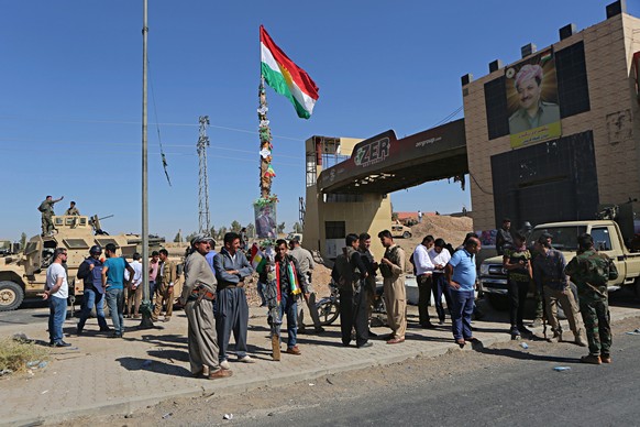 A picture of Massoud Barzani, the President of Iraq&#039;s autonomous Kurdish region, and a Kurdish flag are displayed as Kurdish security forces stand guard in Altun Kupri, on the outskirts of Irbil, ...