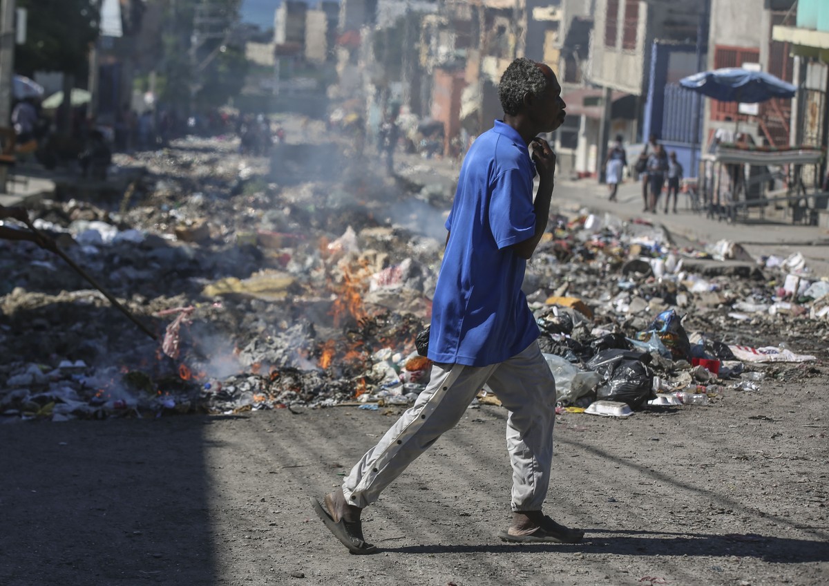 A man walks past burning garbage in downtown Port-au-Prince, Haiti, Monday, Dec. 9, 2024. (AP Photo/Odelyn Joseph)