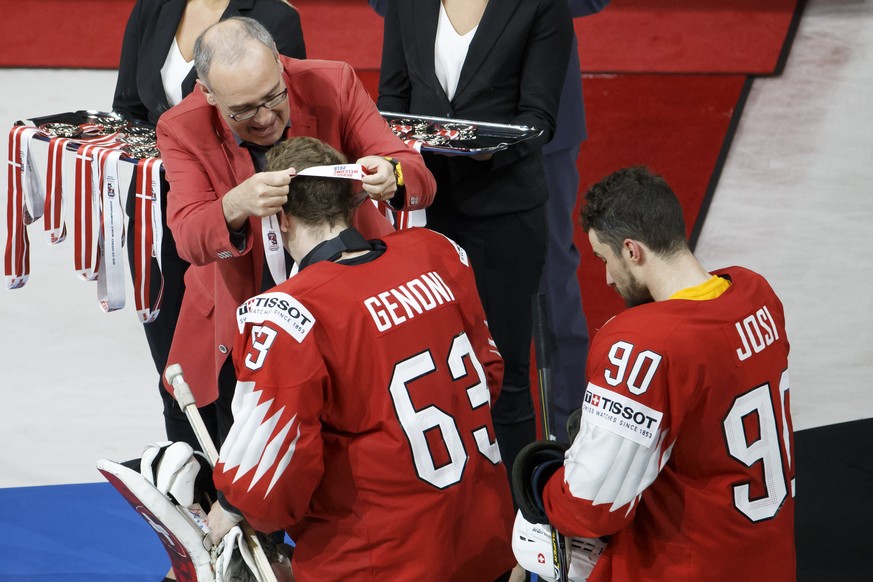 Swiss Defense and Sport Minister Guy Parmelin, left, gives the silver medal to Switzerland&#039;s goaltender Leonardo Genoni #63 past Switzerland&#039;s defender Roman Josi, after losing agains team S ...